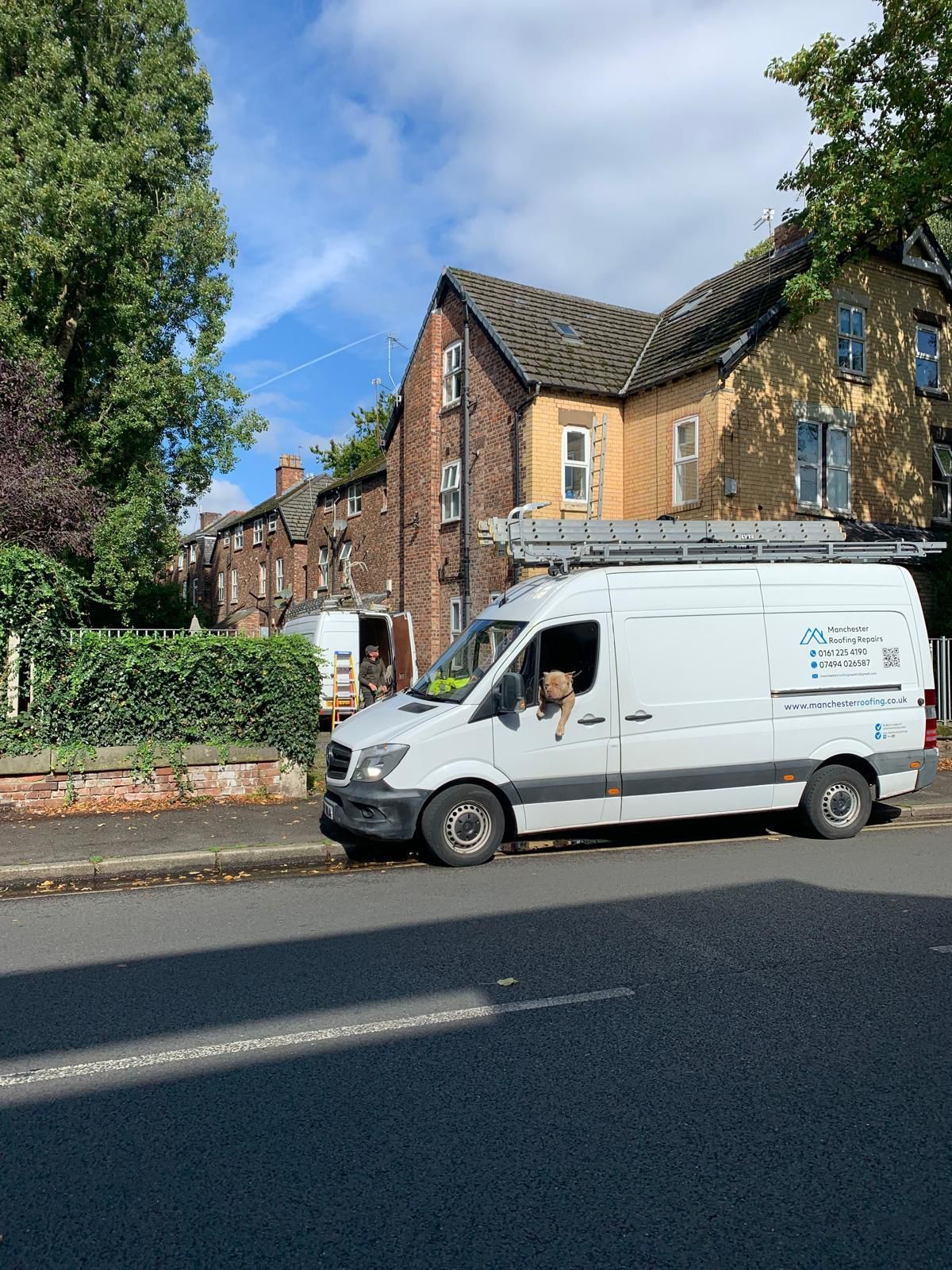 A white van is parked on the side of the road in front of a building.