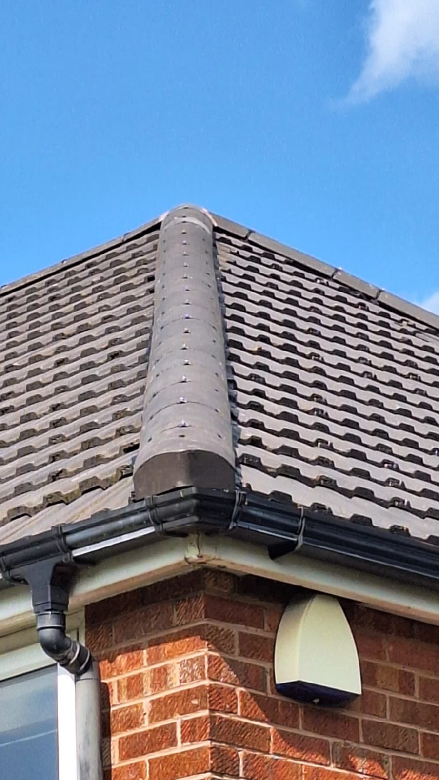 A close up of a roof of a house with a blue sky in the background.