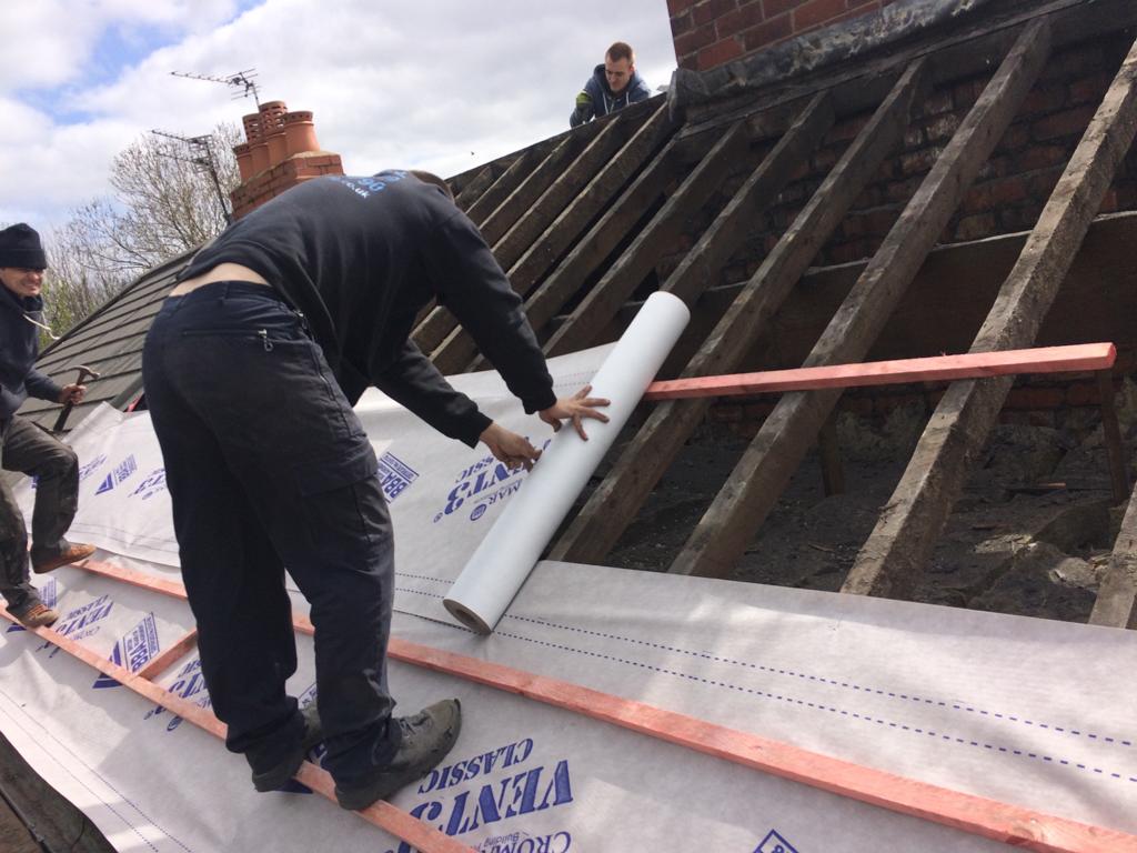 A picture of one of our roofers in Manchester applying underfelt to a roof