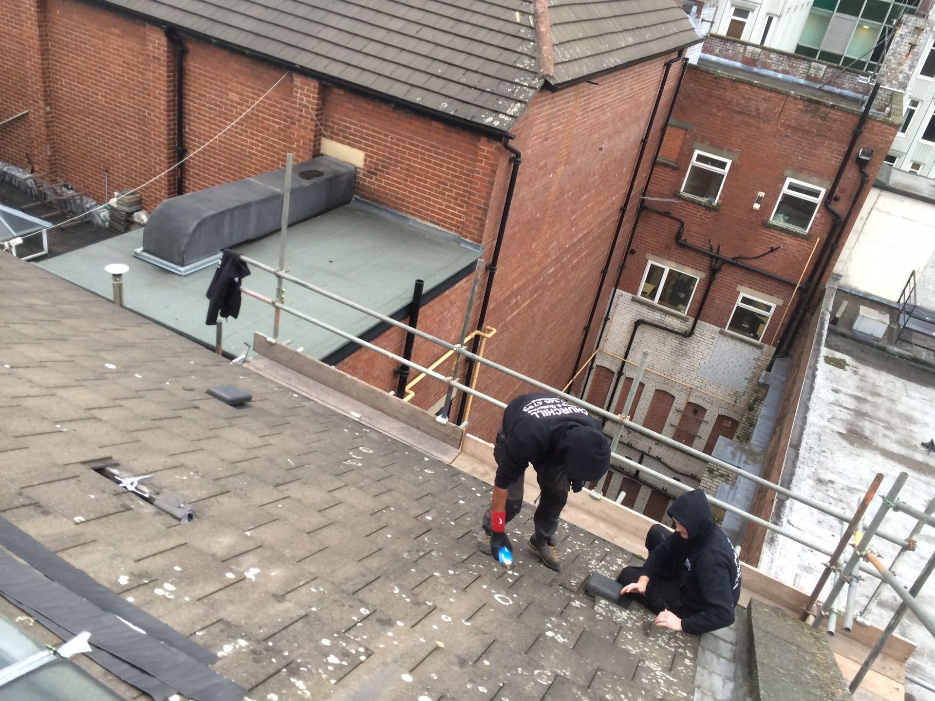 A picture of a roof tile repair being carried out by two roofers from Manchester roofing