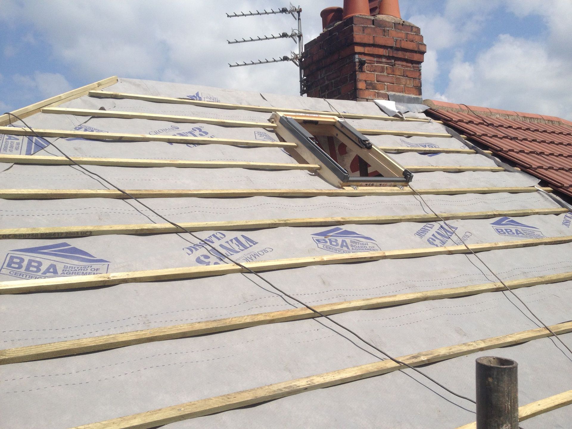 A picture of a hiped roof being replaced by Roofers Manchester