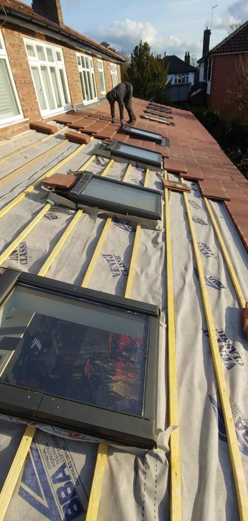 A picture of a roof being installed with skylights and tiles