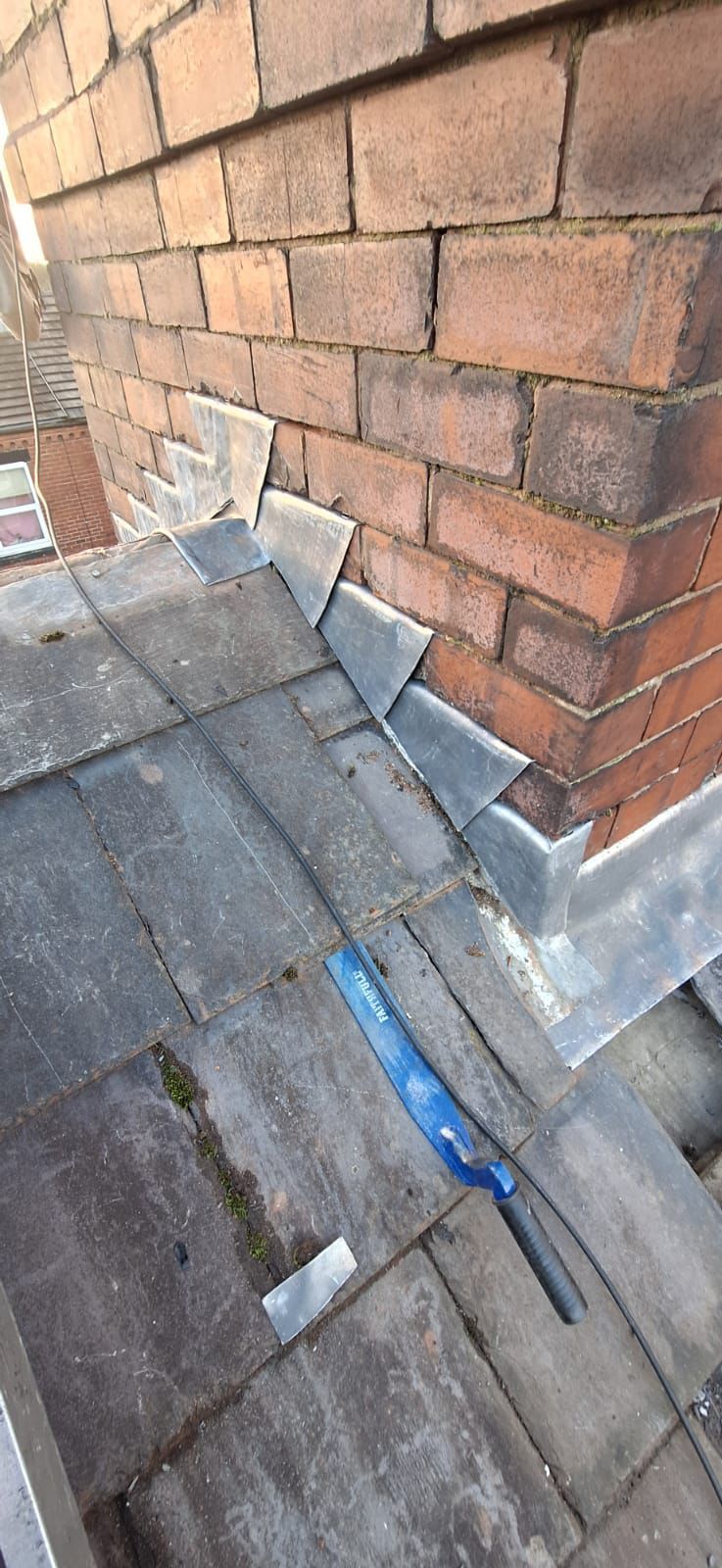 Brick chimney with lead flashing on a slate roof.