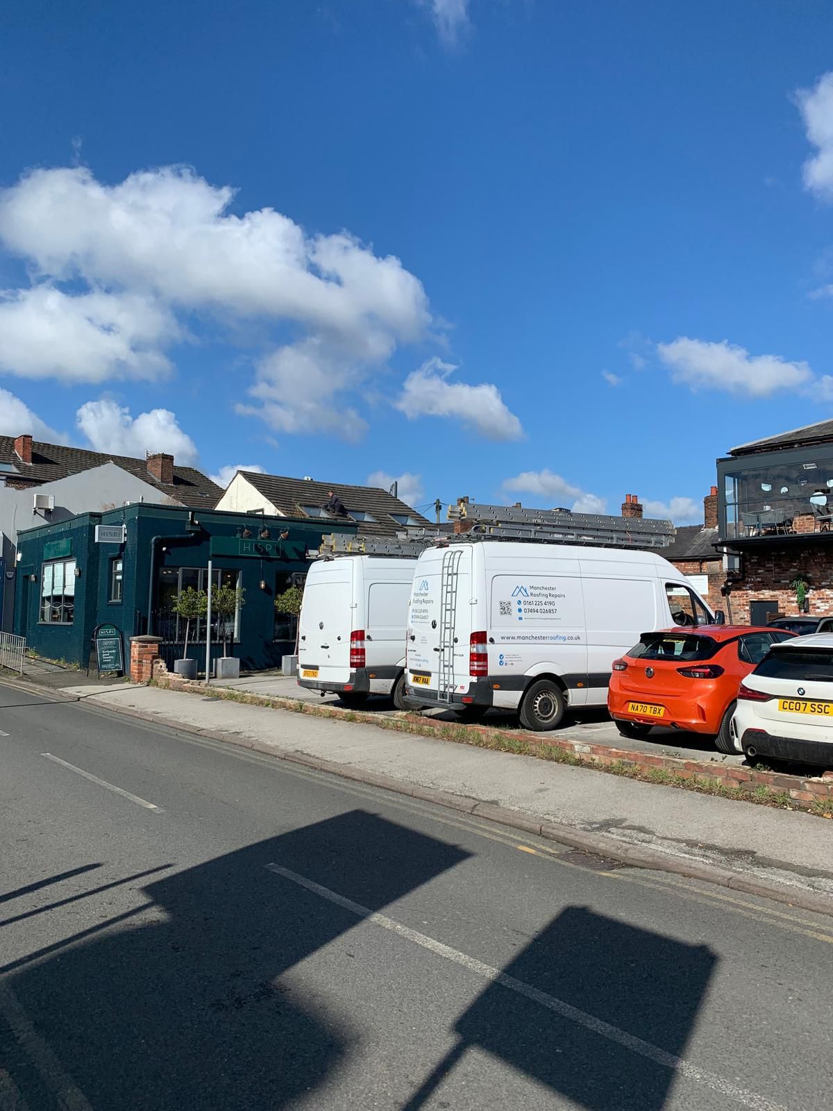 A row of vans are parked on the side of the road in front of a building.