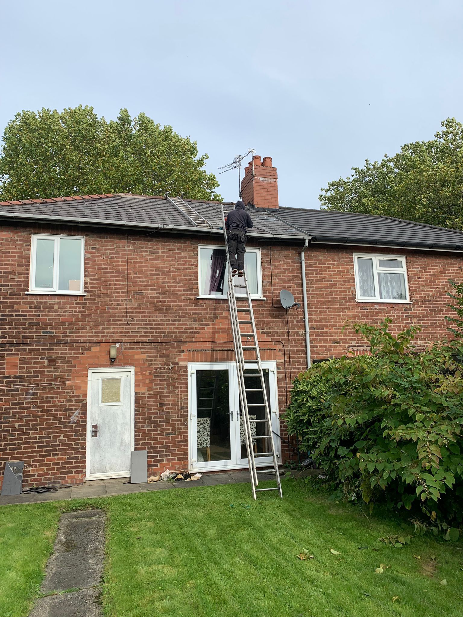 A picture of a roofer on ladders carrying out a roof repair