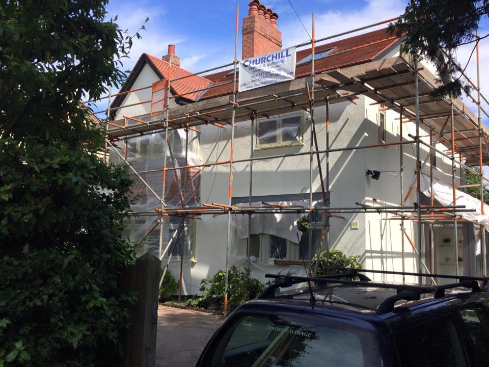 A picture of a large white detached property undergoing a fascia and soffit replacement by Roofers Manchester