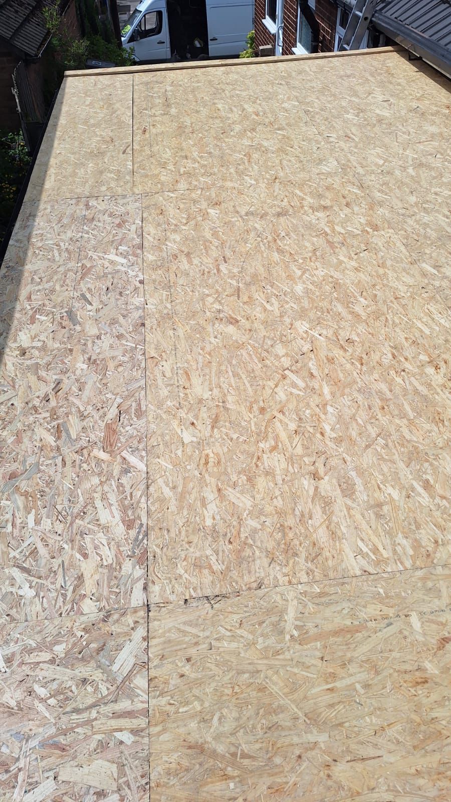 A large piece of plywood is sitting on top of a roof.