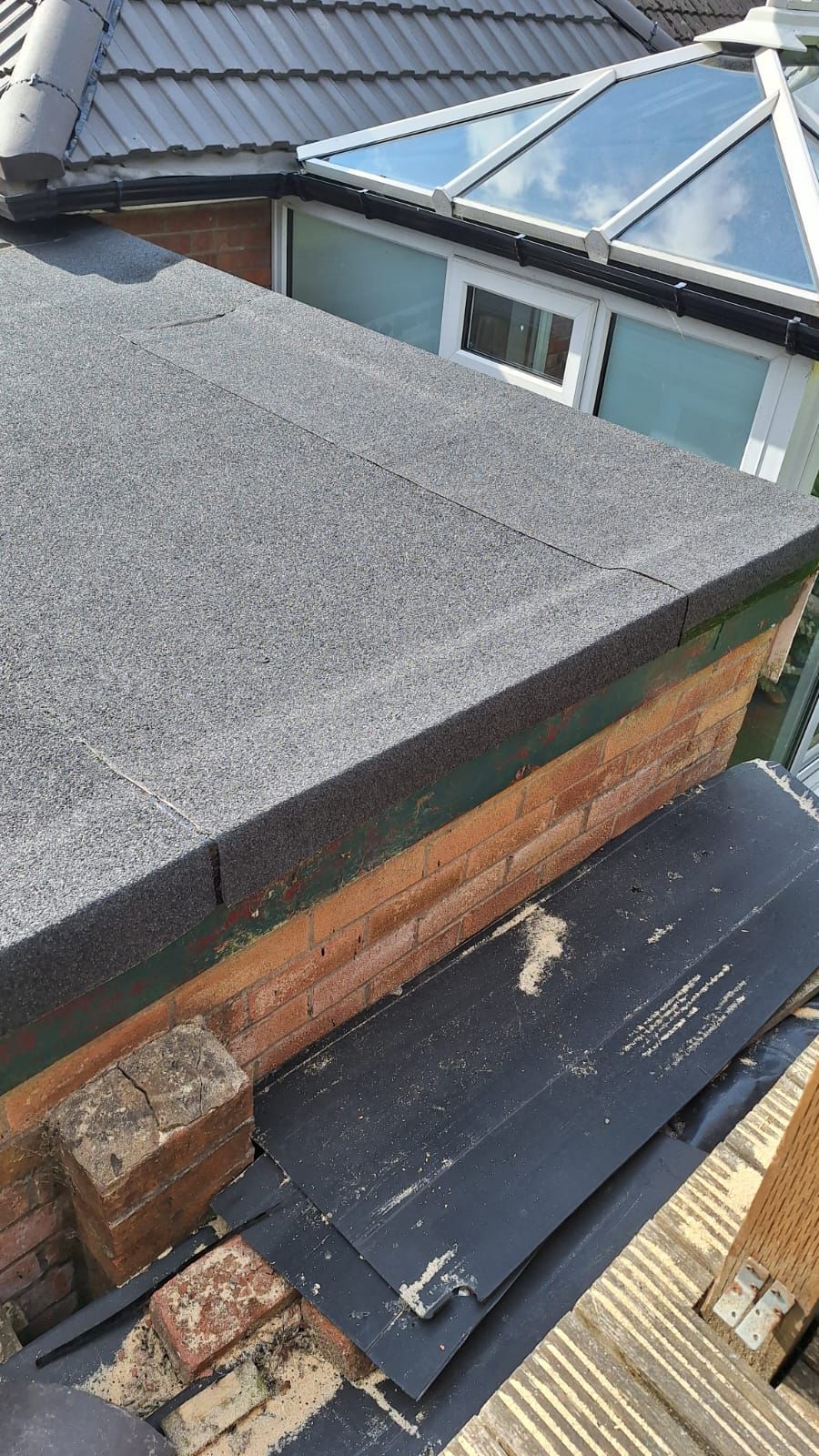 A close up of a roof with a wooden ledge and bricks on it.