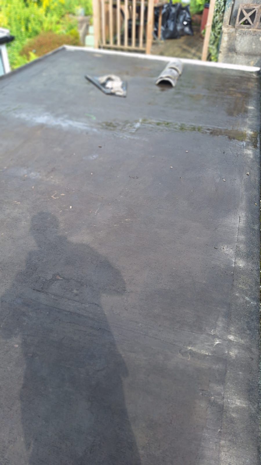 A black roof with a shadow of a person on it.
