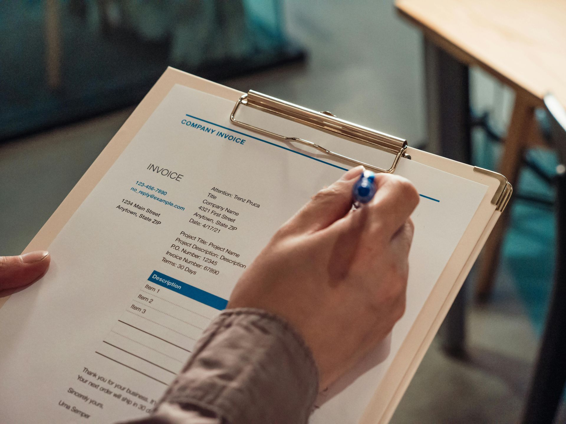 Person writing on a clipboard with a form, in a well-lit indoor setting.