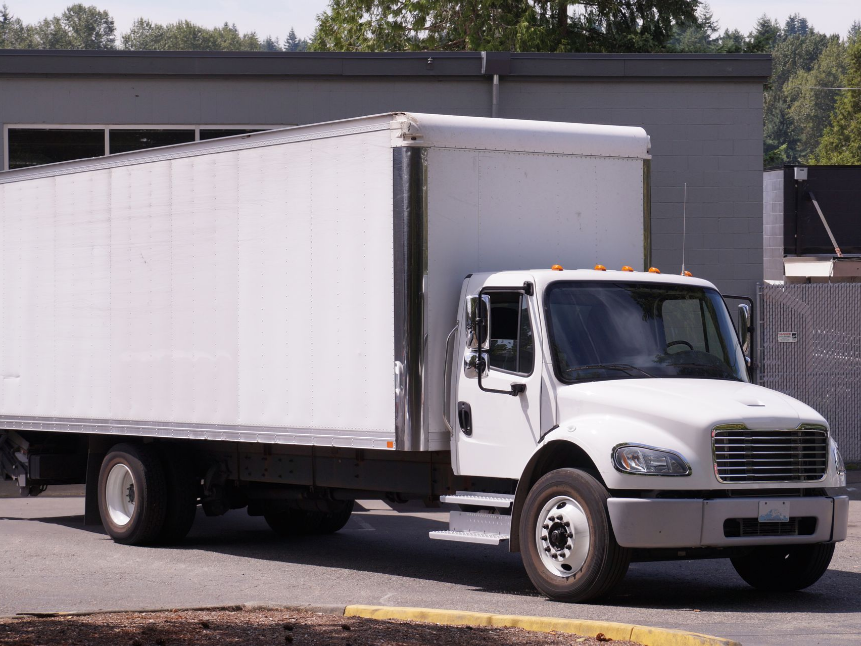White box truck parked in front of a building.