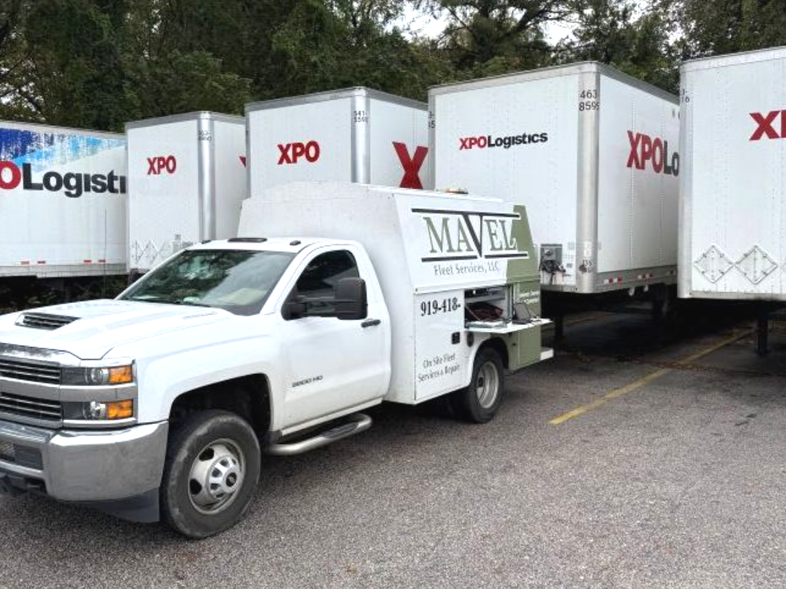 White service truck parked near white XPO Logistics trailers.