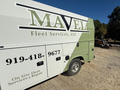 White and green Mavel Fleet Services truck on gravel, blue sky background.