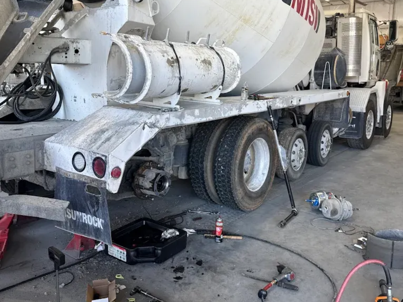 Cement truck in a garage with tools for repair.
