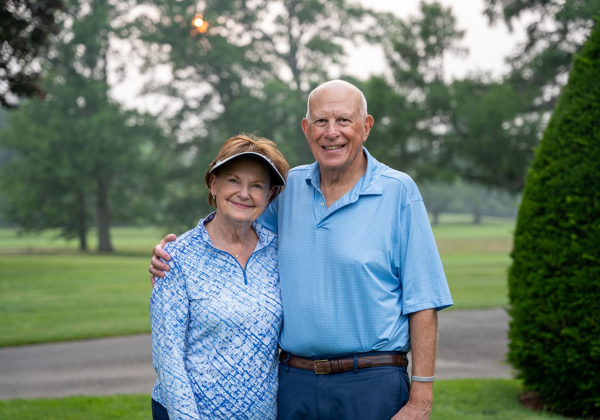 A man and a woman are posing for a picture on a golf course.