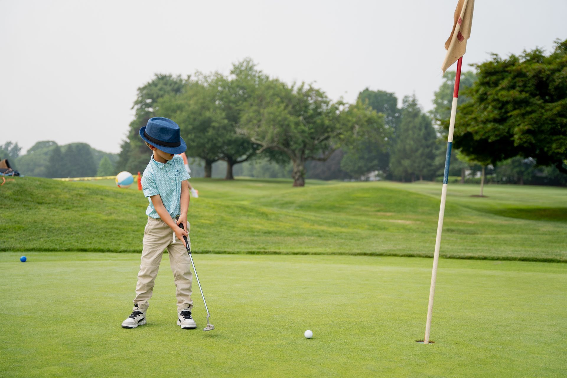 A young boy is playing golf on a golf course.