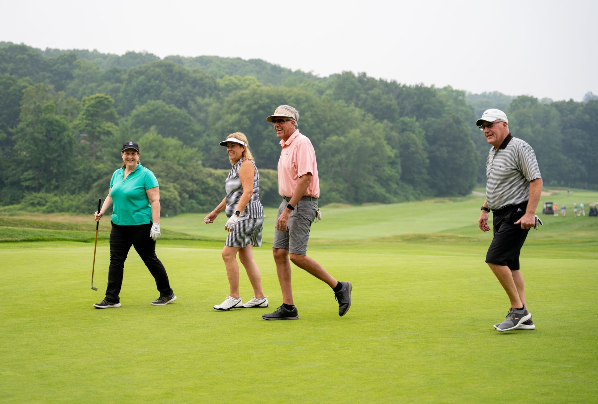 A group of people are walking on a golf course.