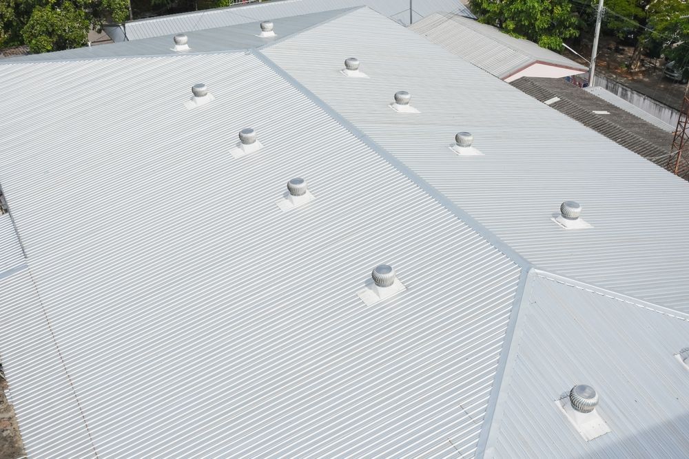 A silver corrugated metal roof with several round vents.