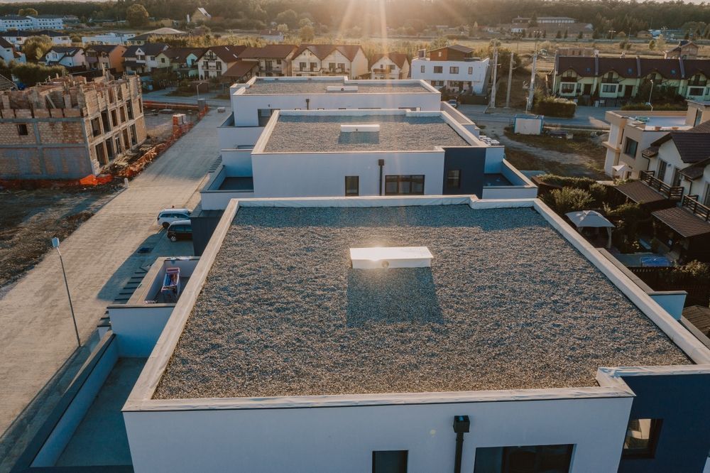 Row of modern white houses with flat roofs, lit by the setting sun.