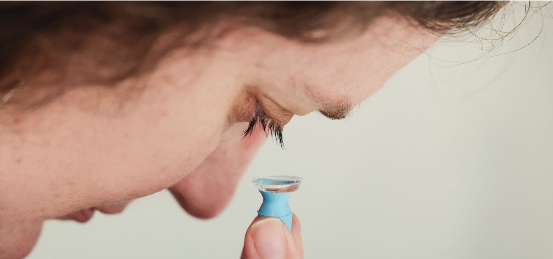 A close up of a person holding a contact lens on their finger.