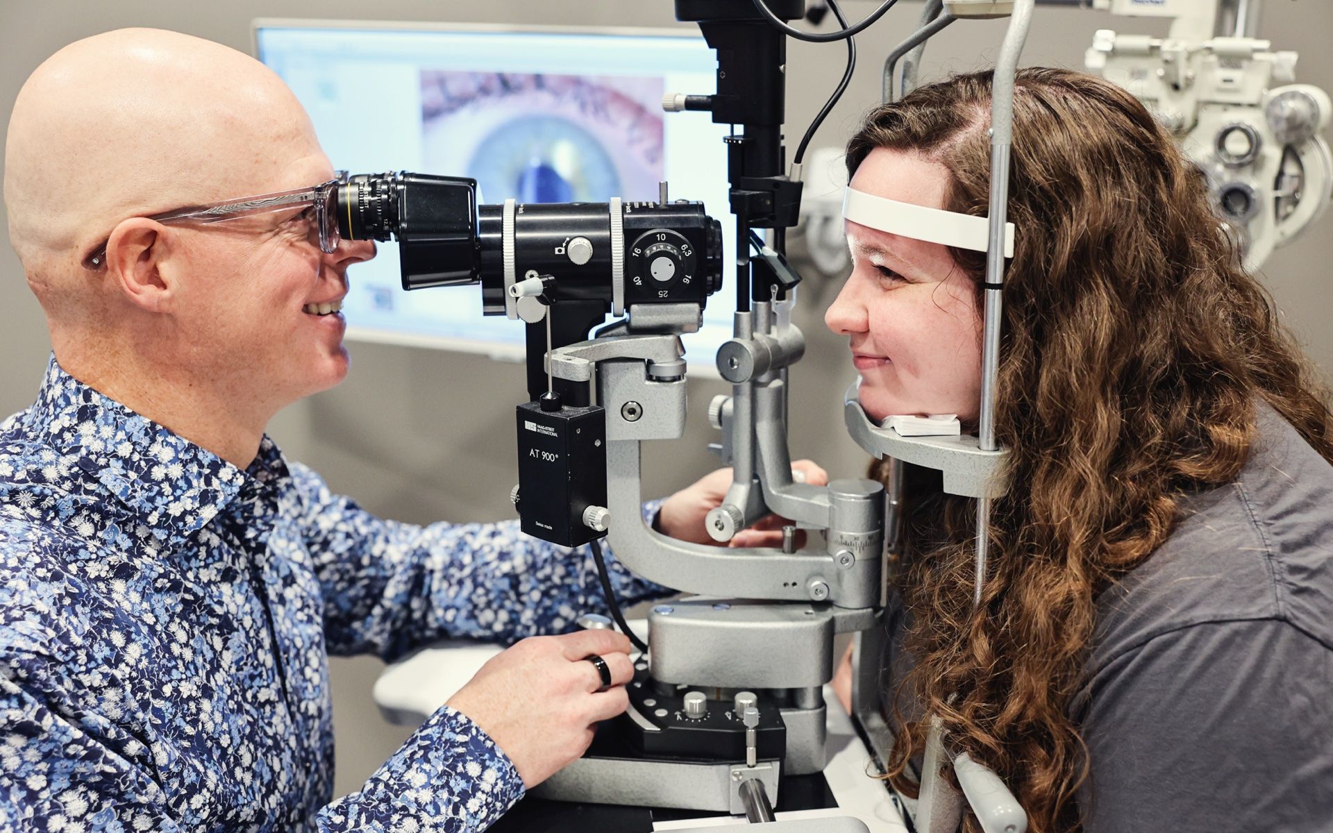 Dr. Lyons examining a patient's eyes with a slit lamp in a clinic.