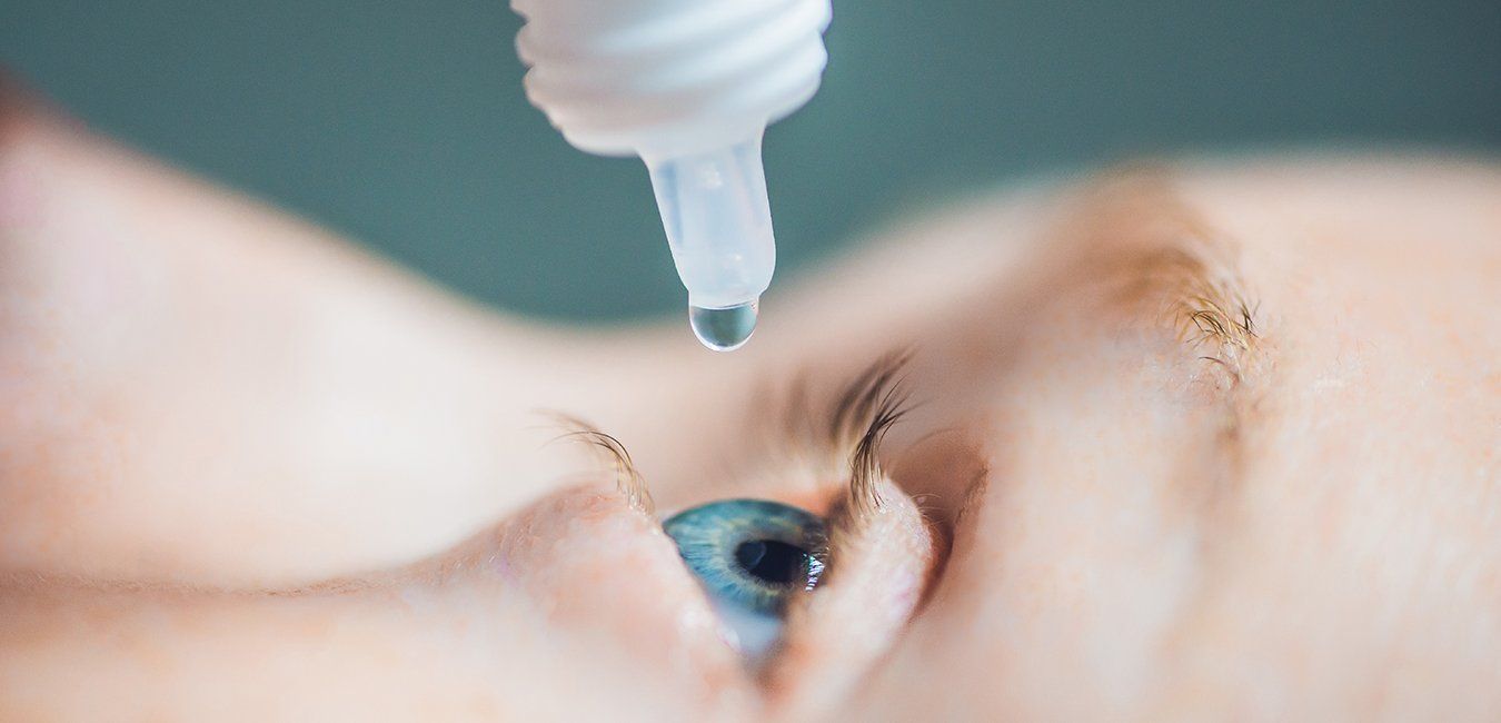 A person is applying eye drops to their eye.