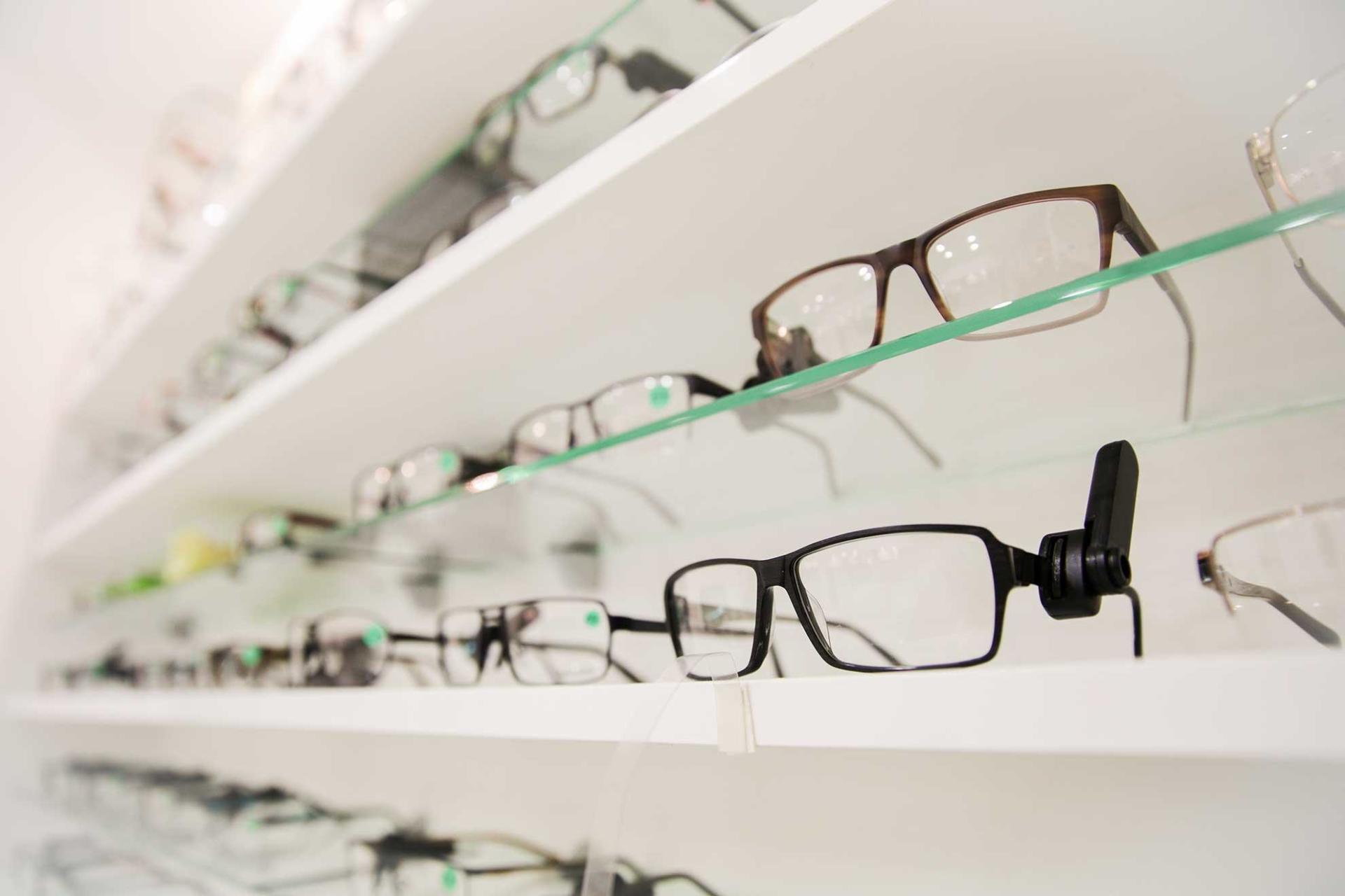 A row of glasses sitting on top of a glass shelf at Focal Pointe Eye Care