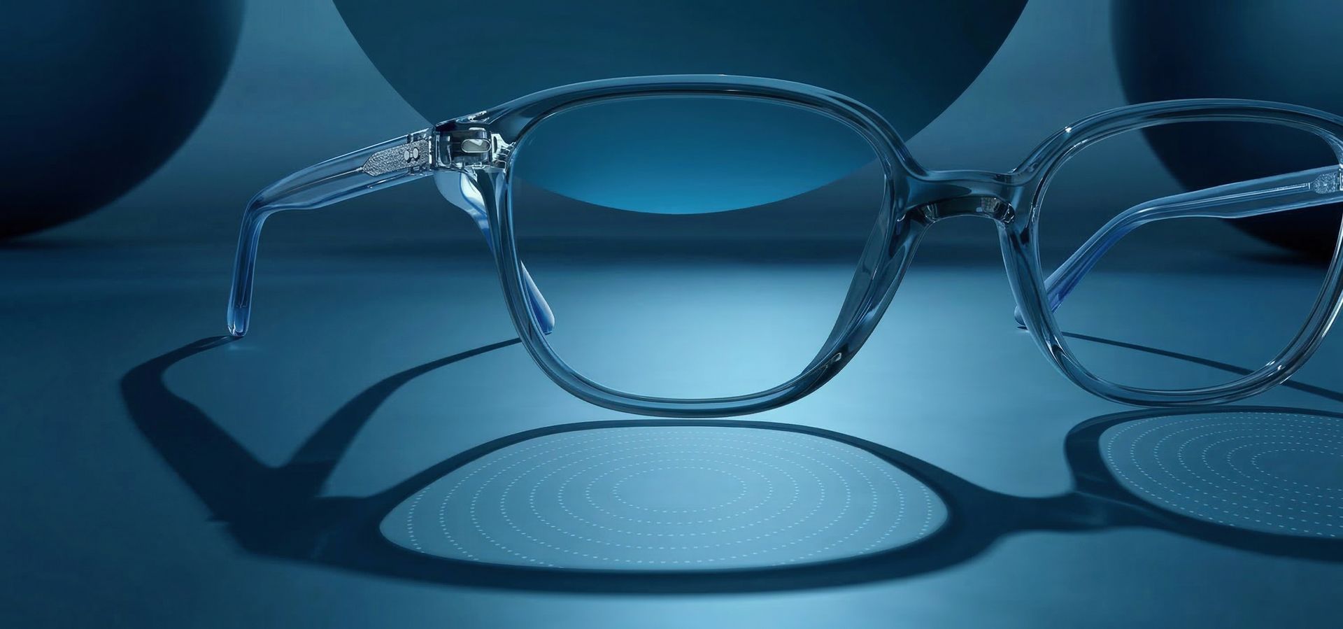 Clear-rimmed eyeglasses centered on a monochromatic blue background, illuminated to cast a prominent shadow.