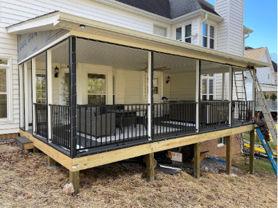 Screened-in porch on a wooden deck, black railings, white trim, attached to a light-colored house.