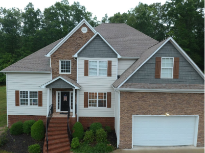 Two-story house with brick and siding, brown shutters, and attached garage.