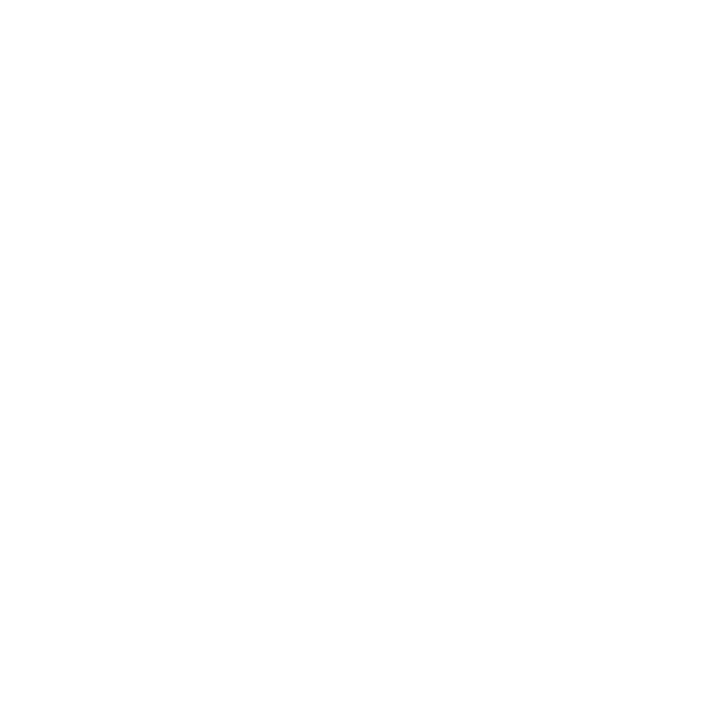 A classic red telephone booth stands on a cobblestone street in front of a historic building.