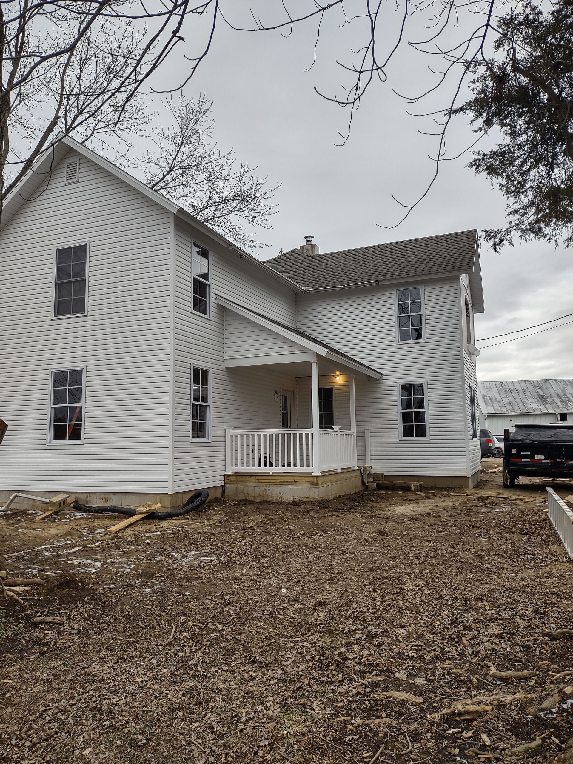A white house with a porch and a truck parked in front of it.