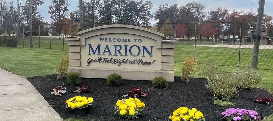 A welcome to marion sign with flowers in front of it
