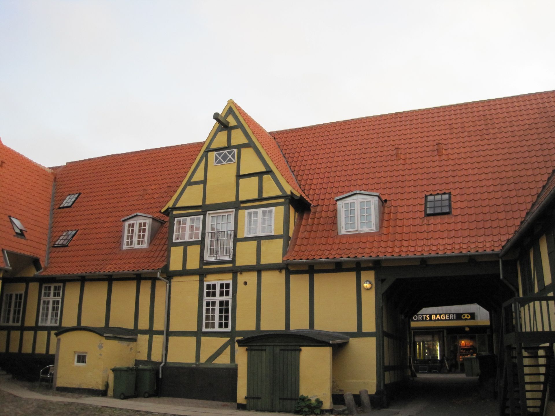 Gul og sort bindingsværksbygning med rødt tegltag og adskillige hvide vinduer.