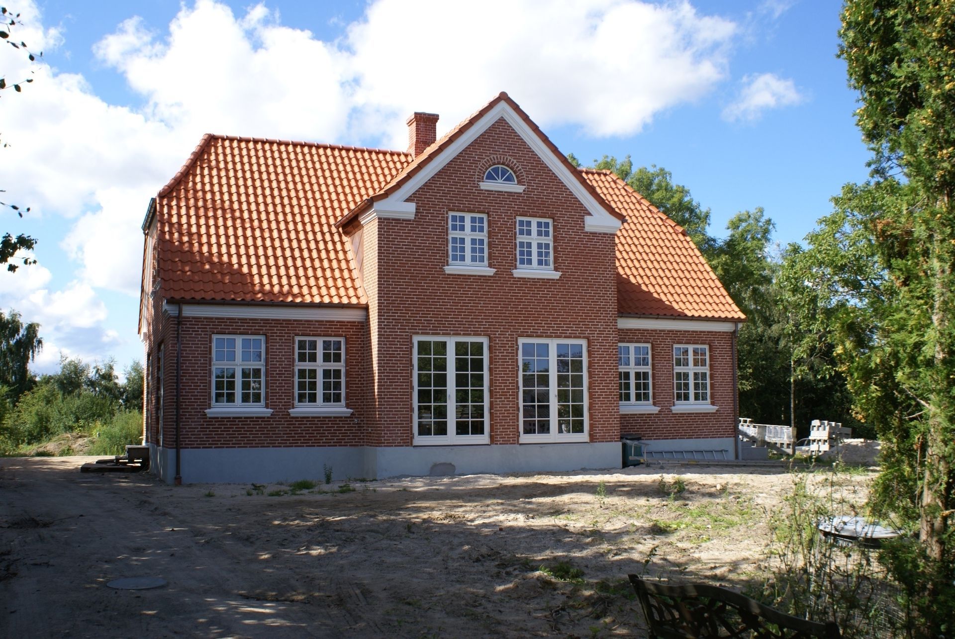 Murstenshus med orange tegltag på en solskinsdag.