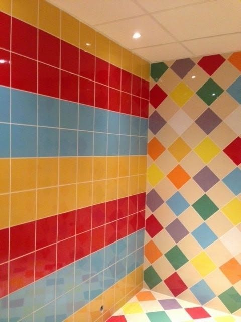 Farverige flisebelagte vægge: røde, blå, gule striber og diamantmønster i forskellige farver.