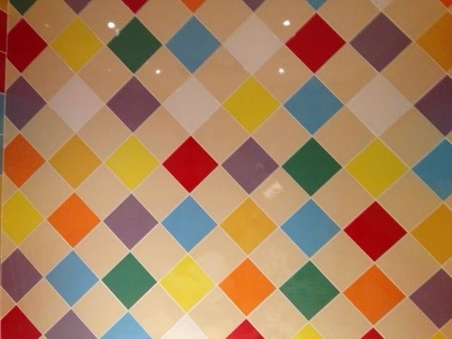 Flerfarvet diamantmønster på en beige væg.