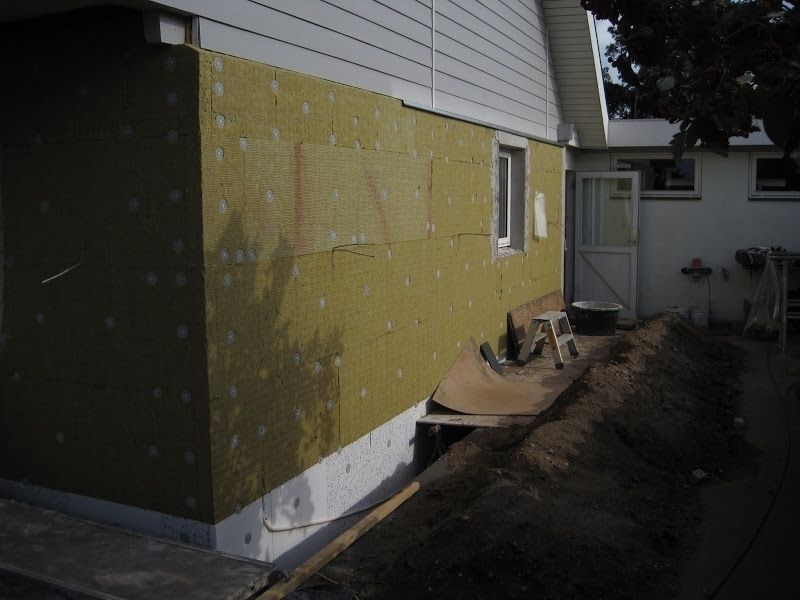 Ydervæg med installeret isolering, ved siden af ​​en jordhøj.