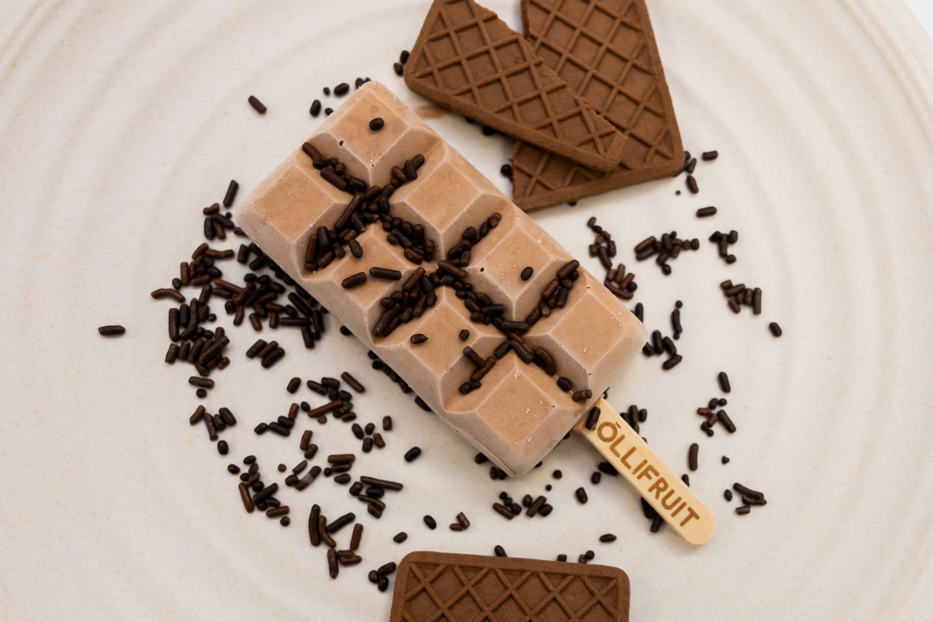 A chocolate ice cream bar with sprinkles on a white plate