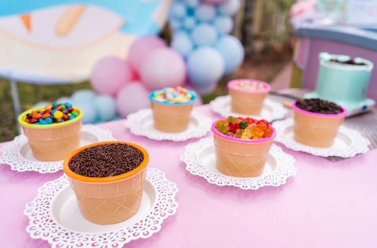 A table topped with ice cream cones filled with different toppings.