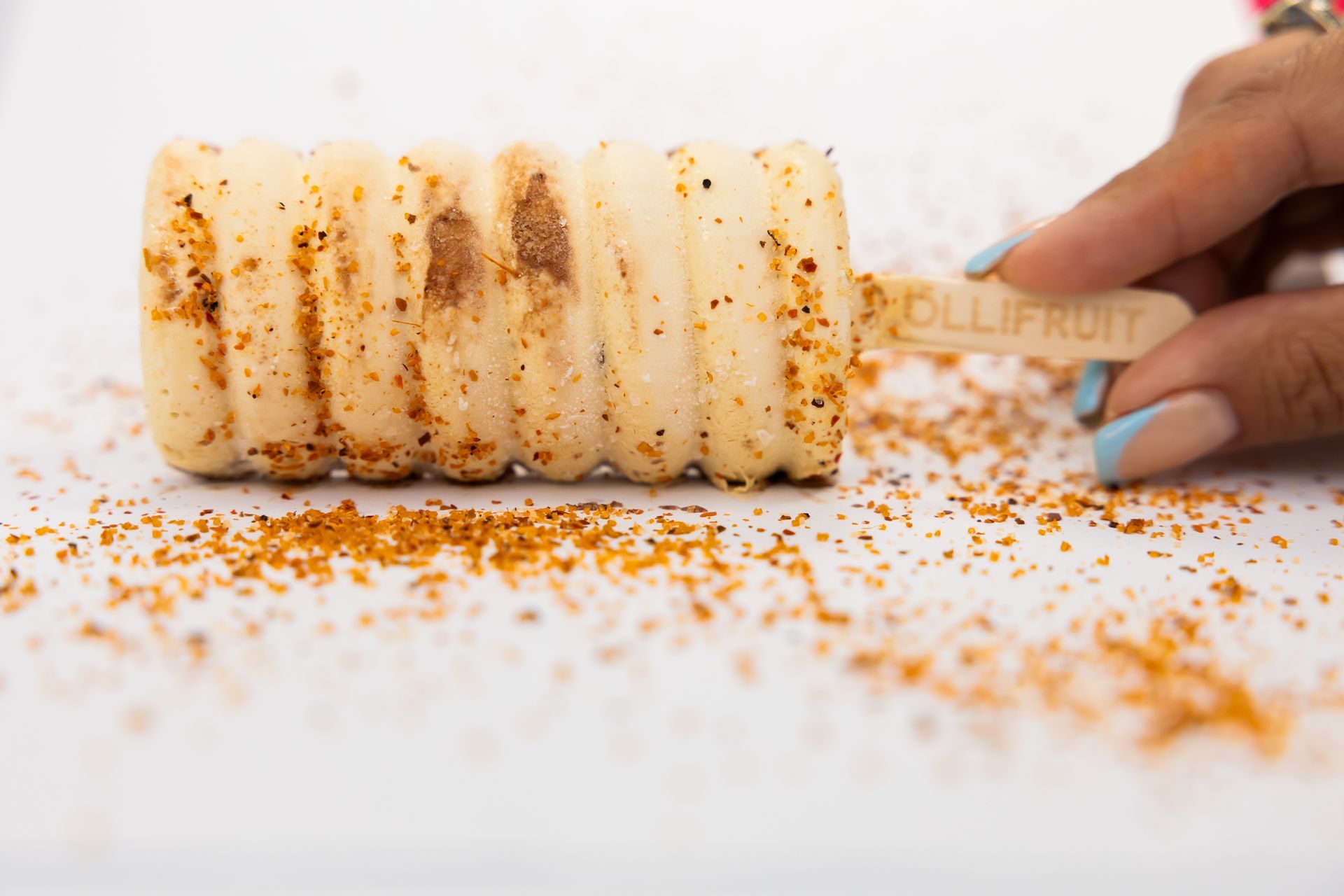 A person is holding a popsicle with sprinkles on it.