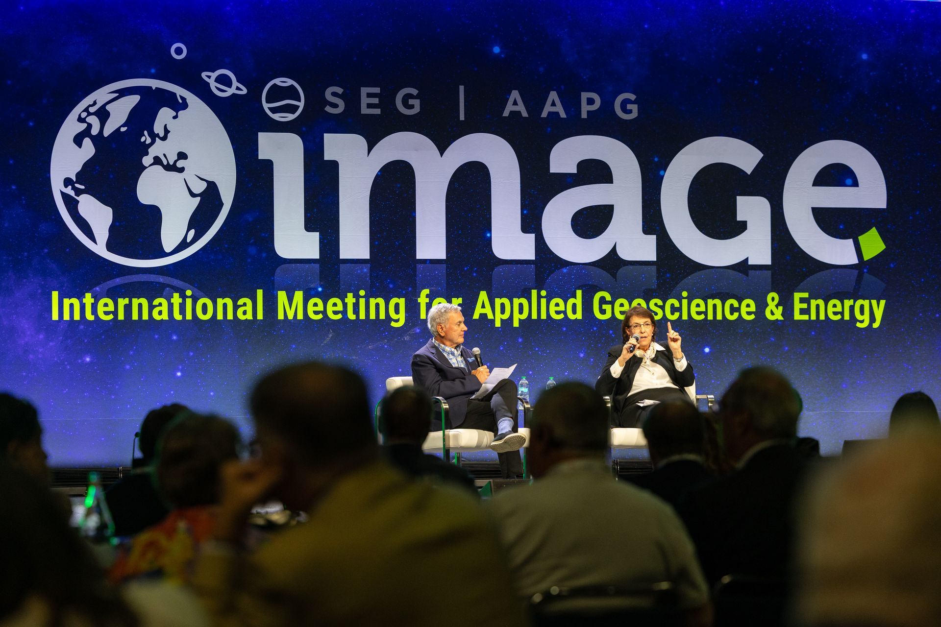 Two people on stage at an “Image” conference, talking in front of a screen with the event logo and a starry background.