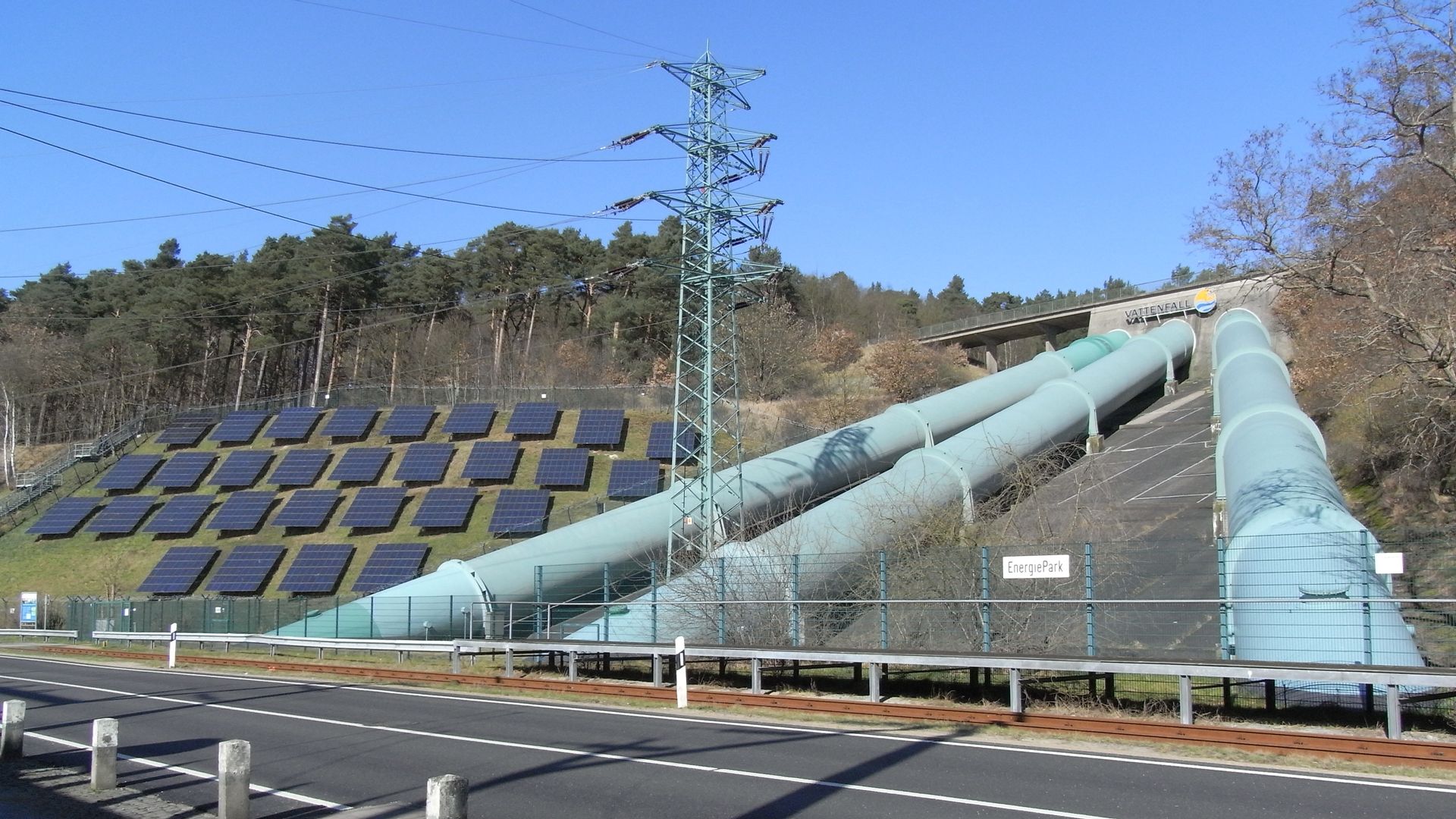 Solar panels, water pipes, and power lines along a road.