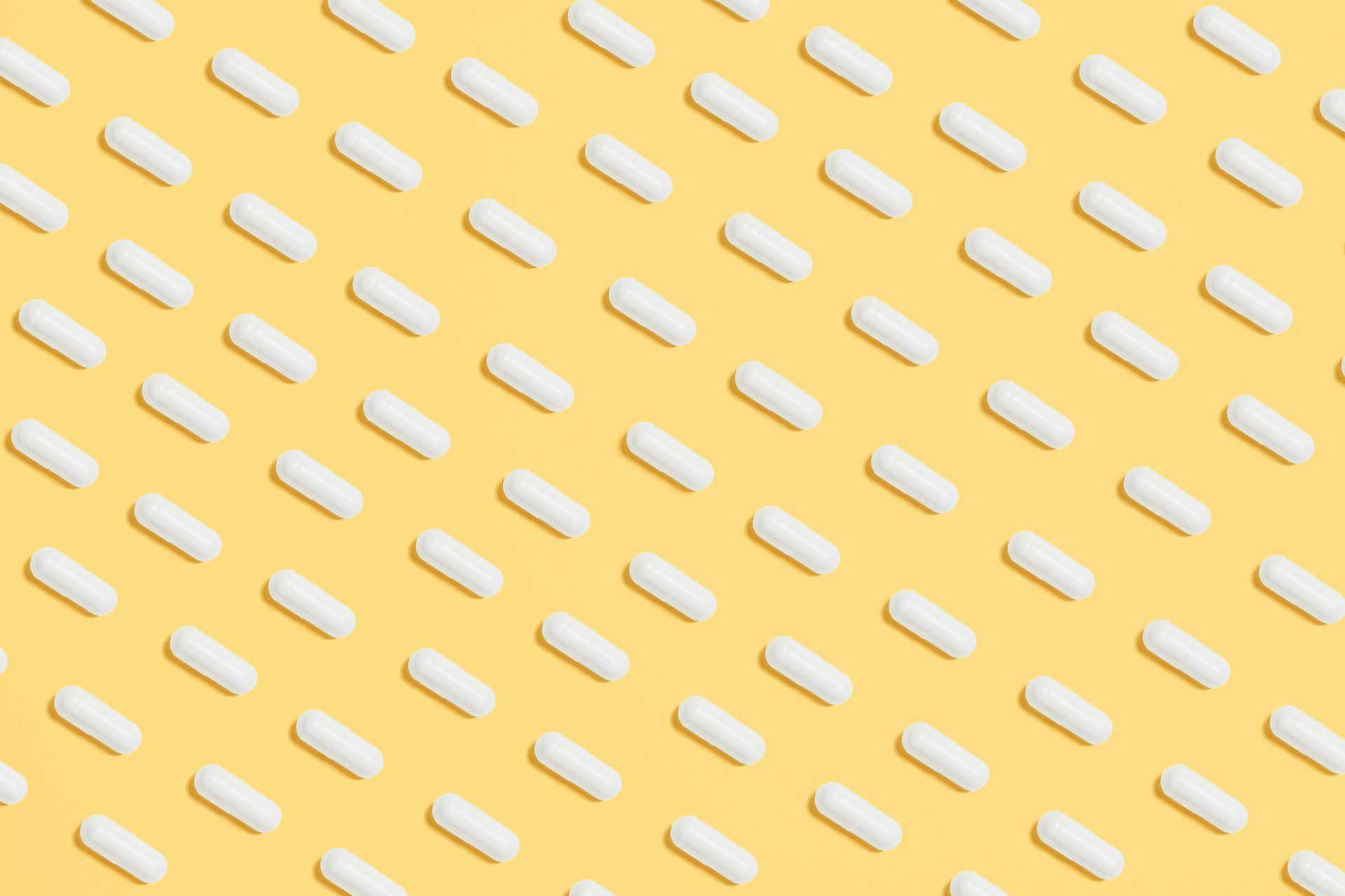 A pattern of white pills on a yellow background.