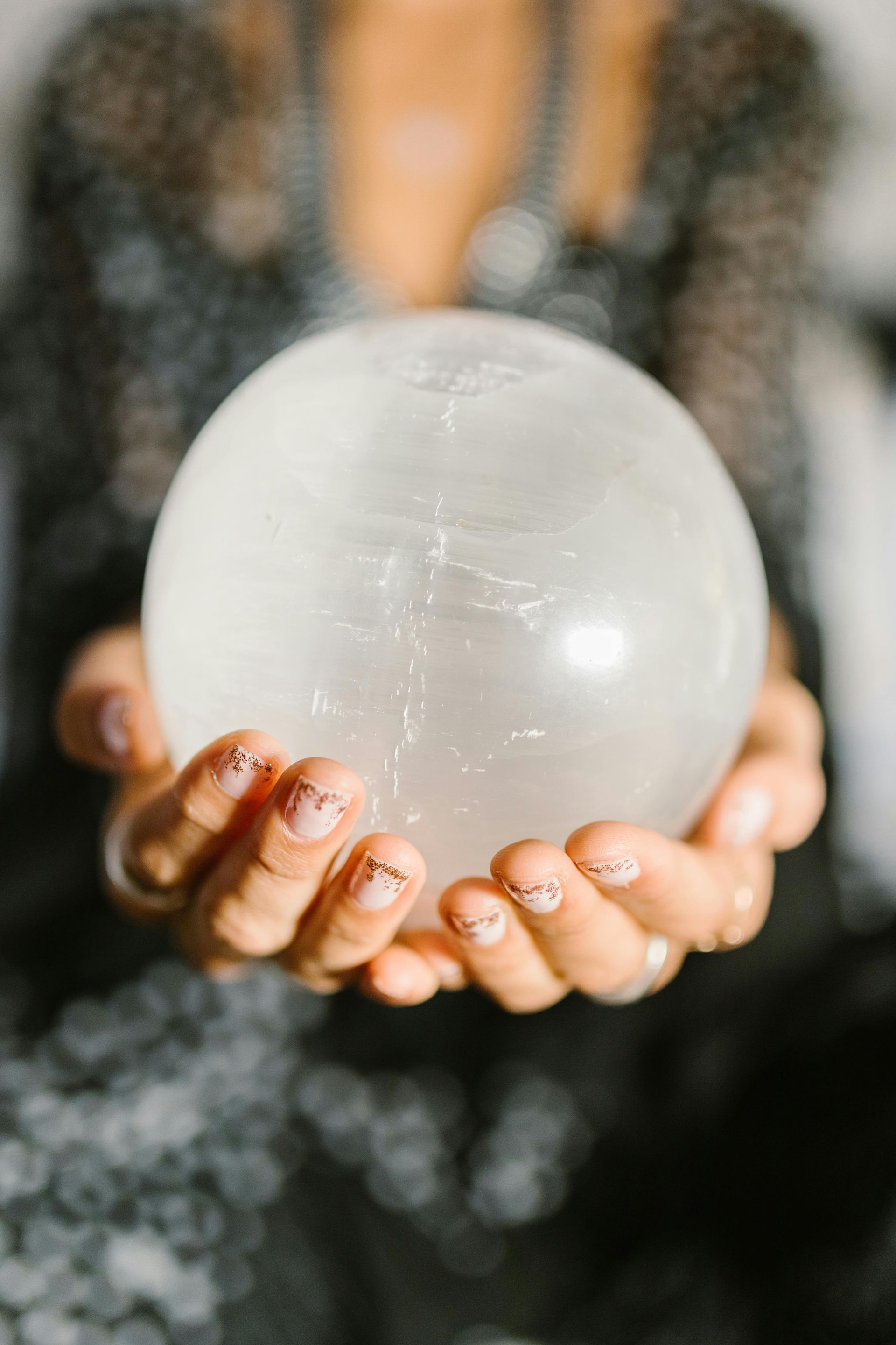 A woman is holding a large white crystal ball in her hands.