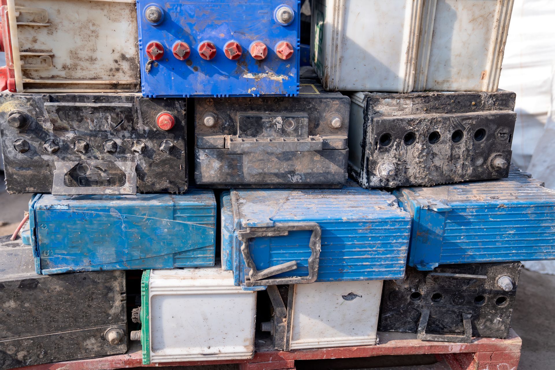 A pile of old batteries are stacked on top of each other on a pallet.