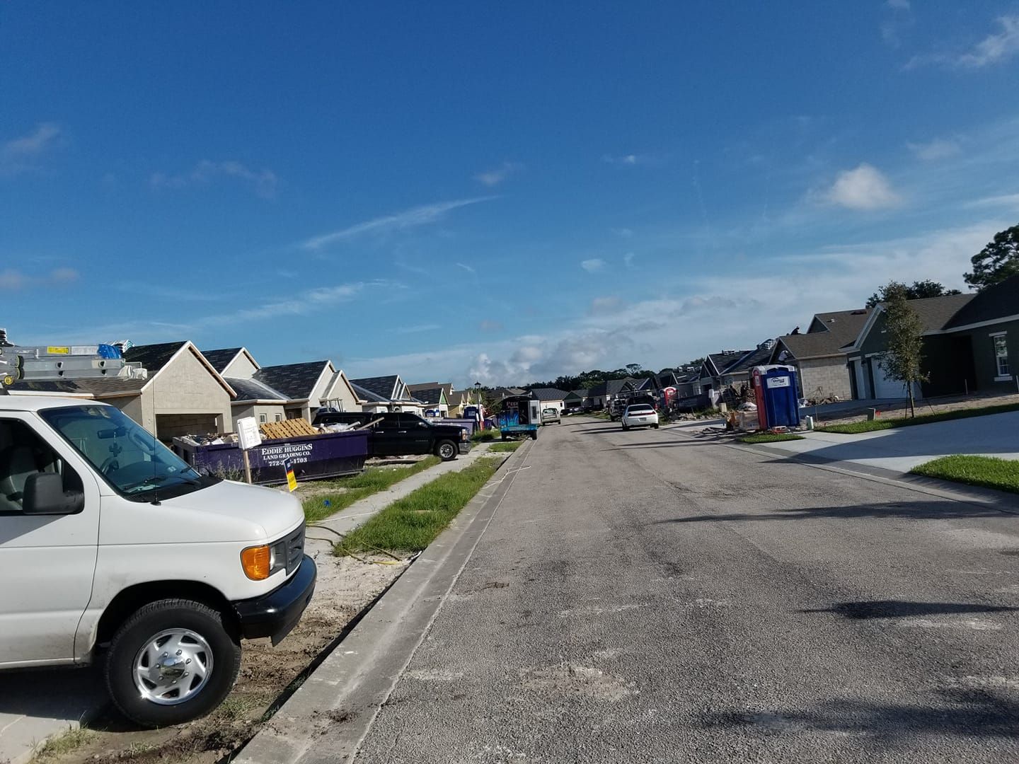 A white van is parked on the side of the road in a residential neighborhood