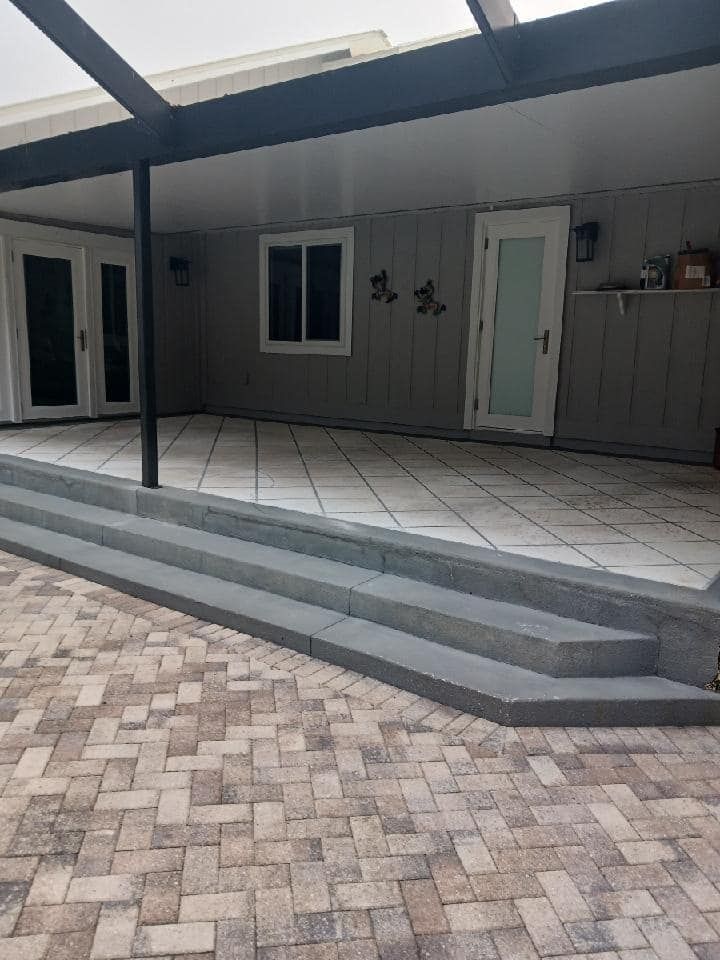 A brick patio with stairs leading up to a house.