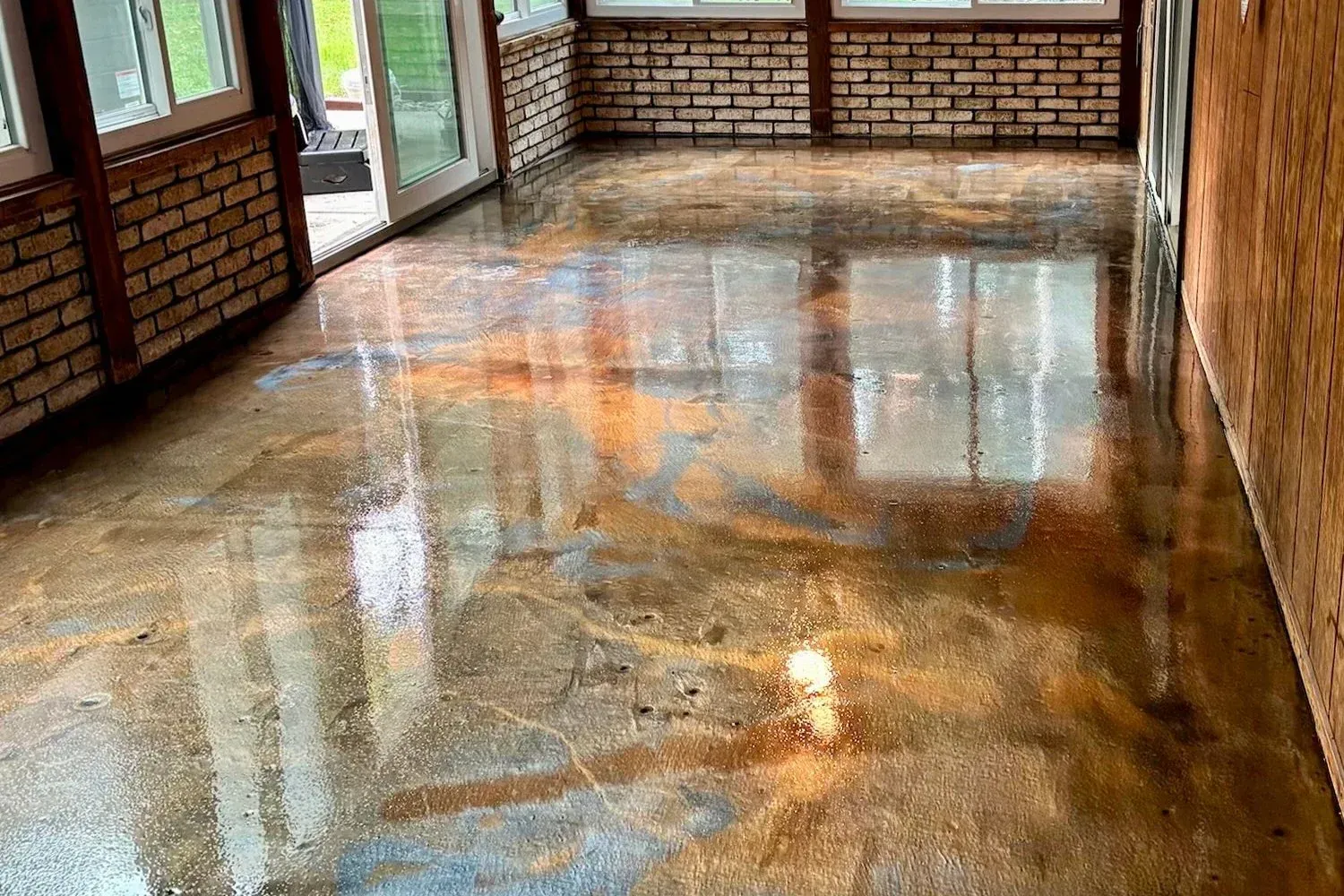 A room with a brick wall and a shiny concrete floor.