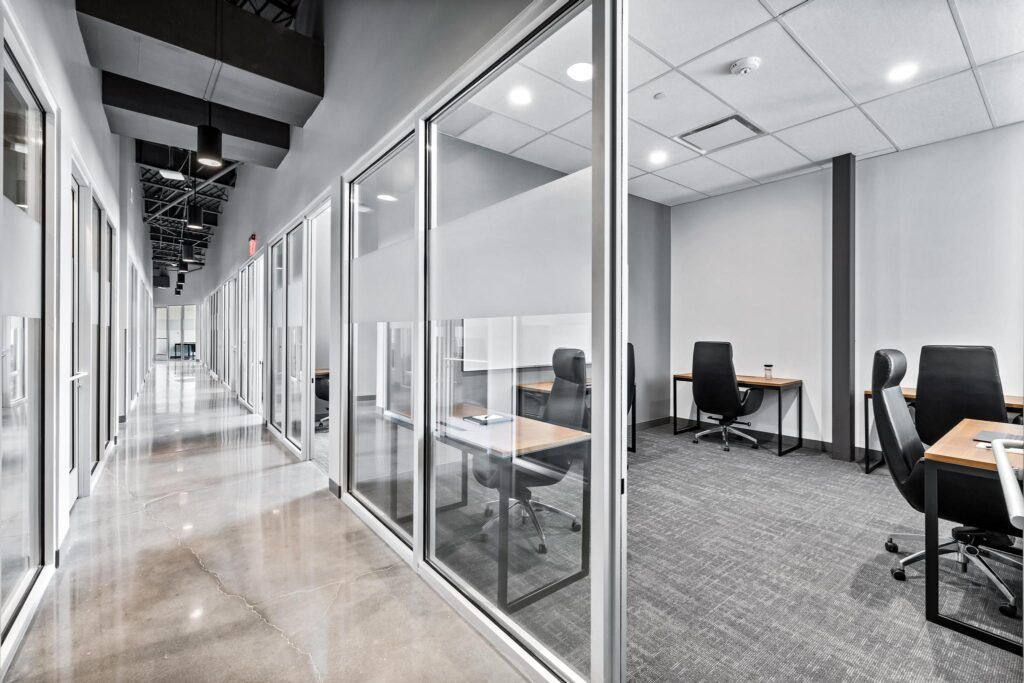 A hallway in an office building with tables and chairs.